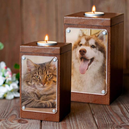 Two small wooden memorial-style candle holders with custom pet photos on the front, each topped with a lit tealight candle, displayed on a rustic wooden surface.